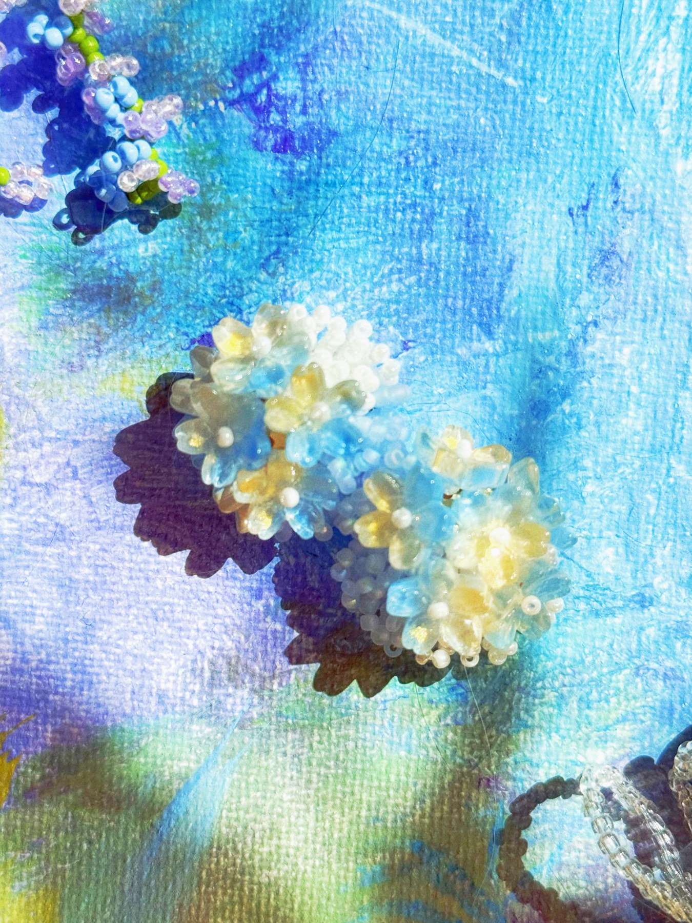 Blue and white beaded flower earrings in dappled garden light