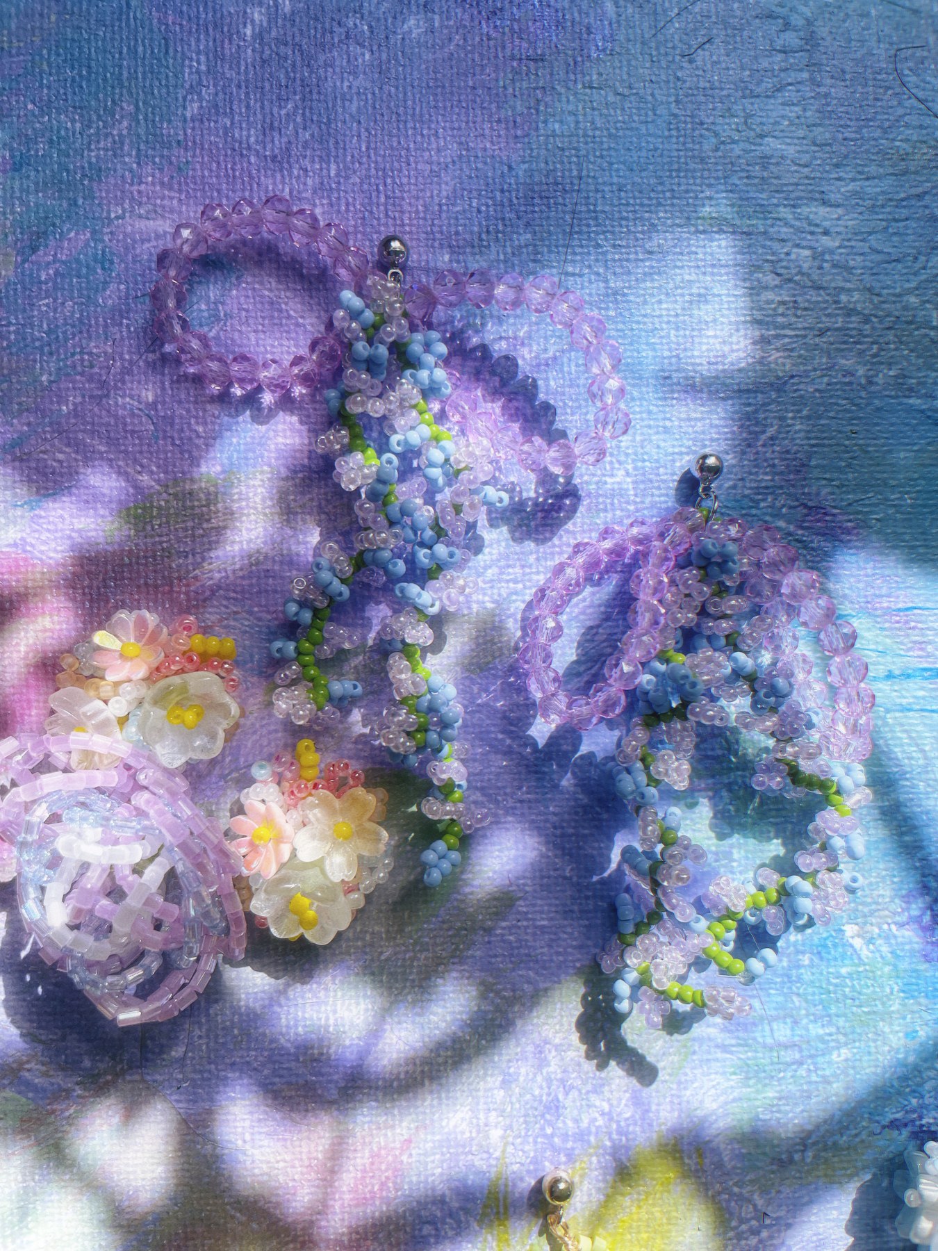Lavender and pastel floral earrings in shifting light