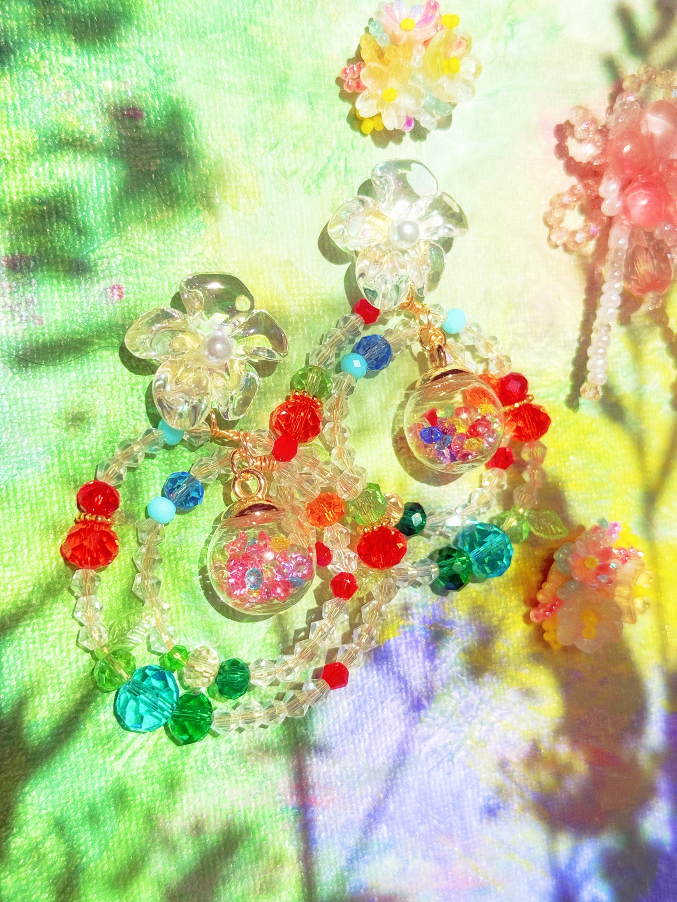 Colorful translucent floral earrings in bright garden light