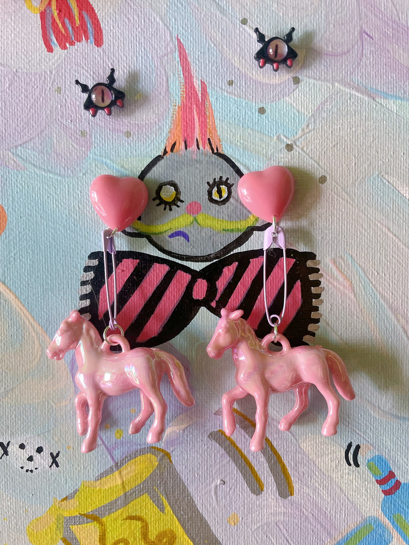 Pink character-inspired earrings with playful striped details